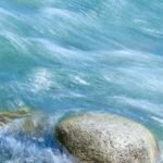 Tranquil long exposure capturing flowing river and rocks in Xinjiang, China.